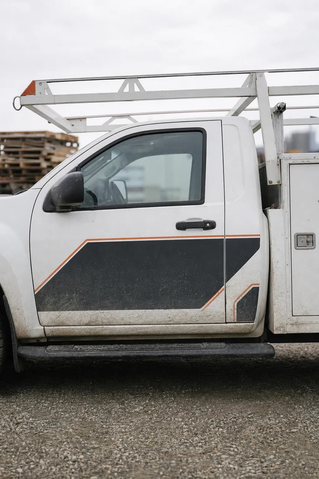 White service pickup with a partial door graphic in a gravel yard